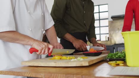 Caucasian-female-chef-teaching-diverse-group-wearing-face-masks