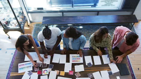 overhead view of team having creative design meeting around wooden table in office