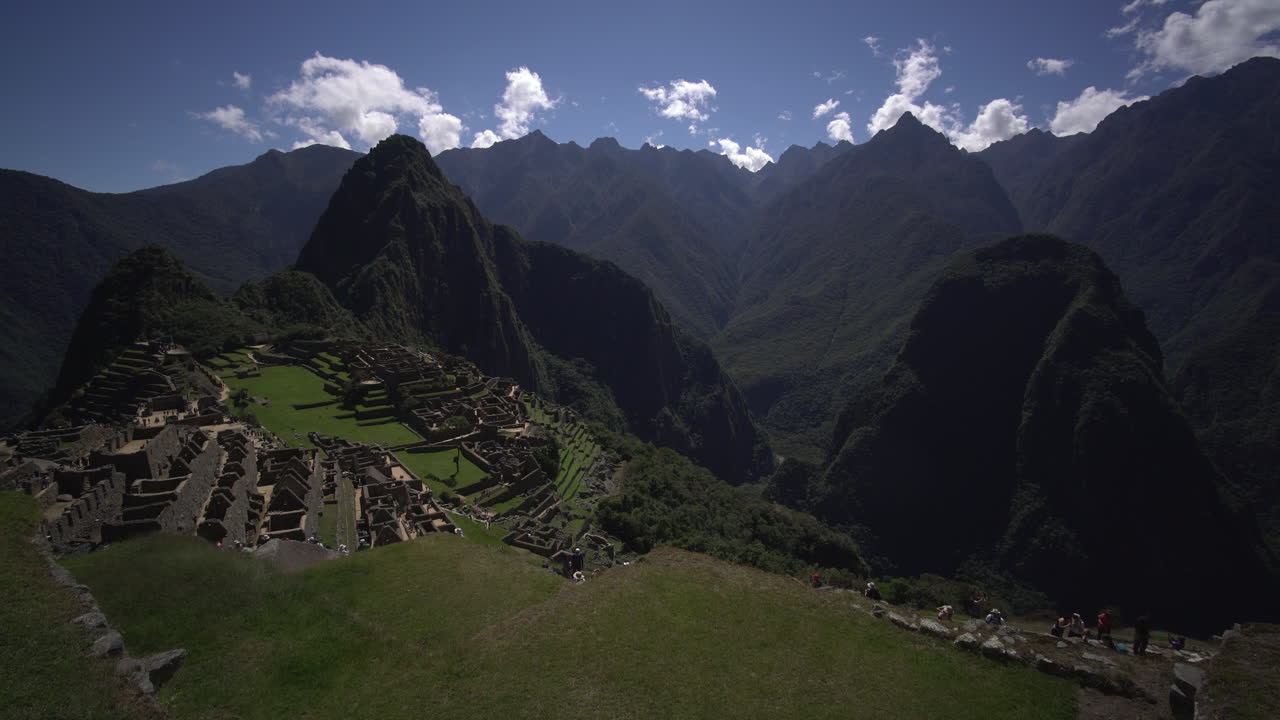 una impresionante vista panorámica de machu picchu, perú, muestra las majestuosas montañas de putu cusi y huayna, también se pueden ver los edificios que los antiguos incas construyeron con estructuras rectangulares.