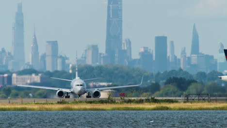 american airlines jet on runway at jfk with manhattan nyc skyline in distance