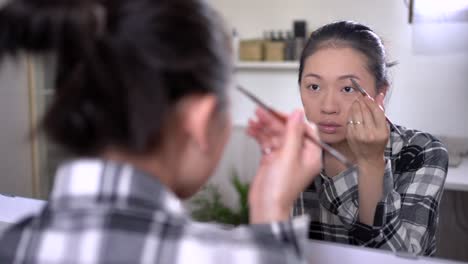 asian woman doing makeup at home