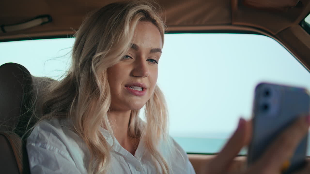 금발이 자동차에서 비디오 통화를 할 때 가까이에서 여성 비디오 통화를합니다.