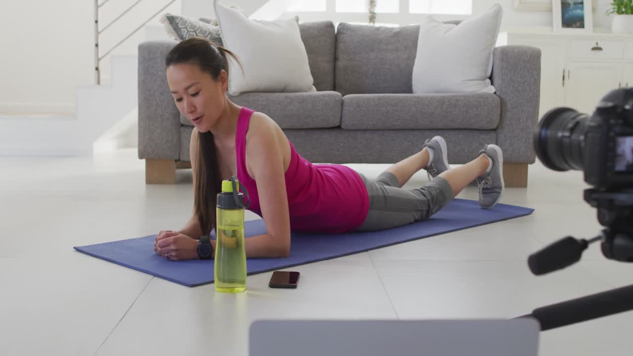 mujer asiática feliz en el tapete, haciendo ejercicio, haciendo vlog de fitness desde casa