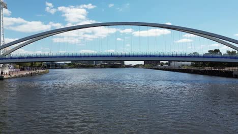 Vuelo-Aéreo-De-Drones-Sobre-Los-Muelles-Del-Muelle-En-La-Ciudad-De-Los-Medios-De-Comunicación-Pasando-Bajo-El-Arco-Del-Puente-Peatonal-En-La-Ciudad-De-Manchester