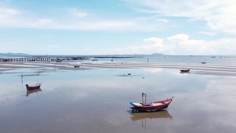 Traditionelle-Fischerboote,-Die-Bei-Ebbe-In-Thailand-Ruhig-Am-Sandstrand-Sitzen---Niedrige-Antenne