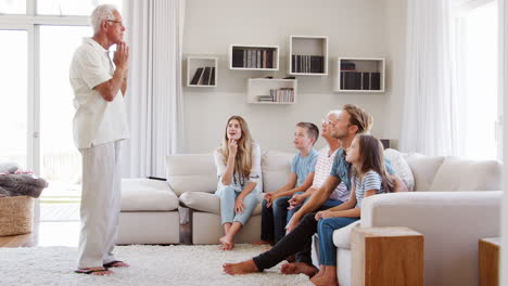 multi generation family sitting on sofa at home playing charades