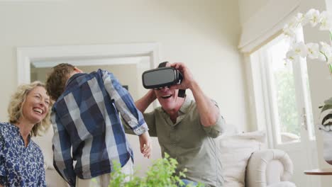 happy senior caucasian couple with grandson using vr headset in living room