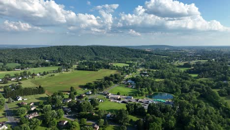 Flying-over-the-lush-green-rural-countryside-with-fields-and-small-clusters-of-houses-on-a-sunny-day