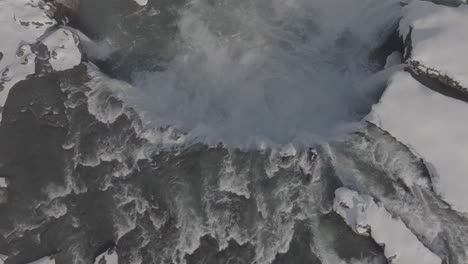 birdseye aerial view of goðafoss waterfall in cold winter landscape of iceland, drone shot