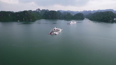 aerial of beautiful limestone mountain landscape in ha long bay vietnam with mega yacht anchored on cloudy day