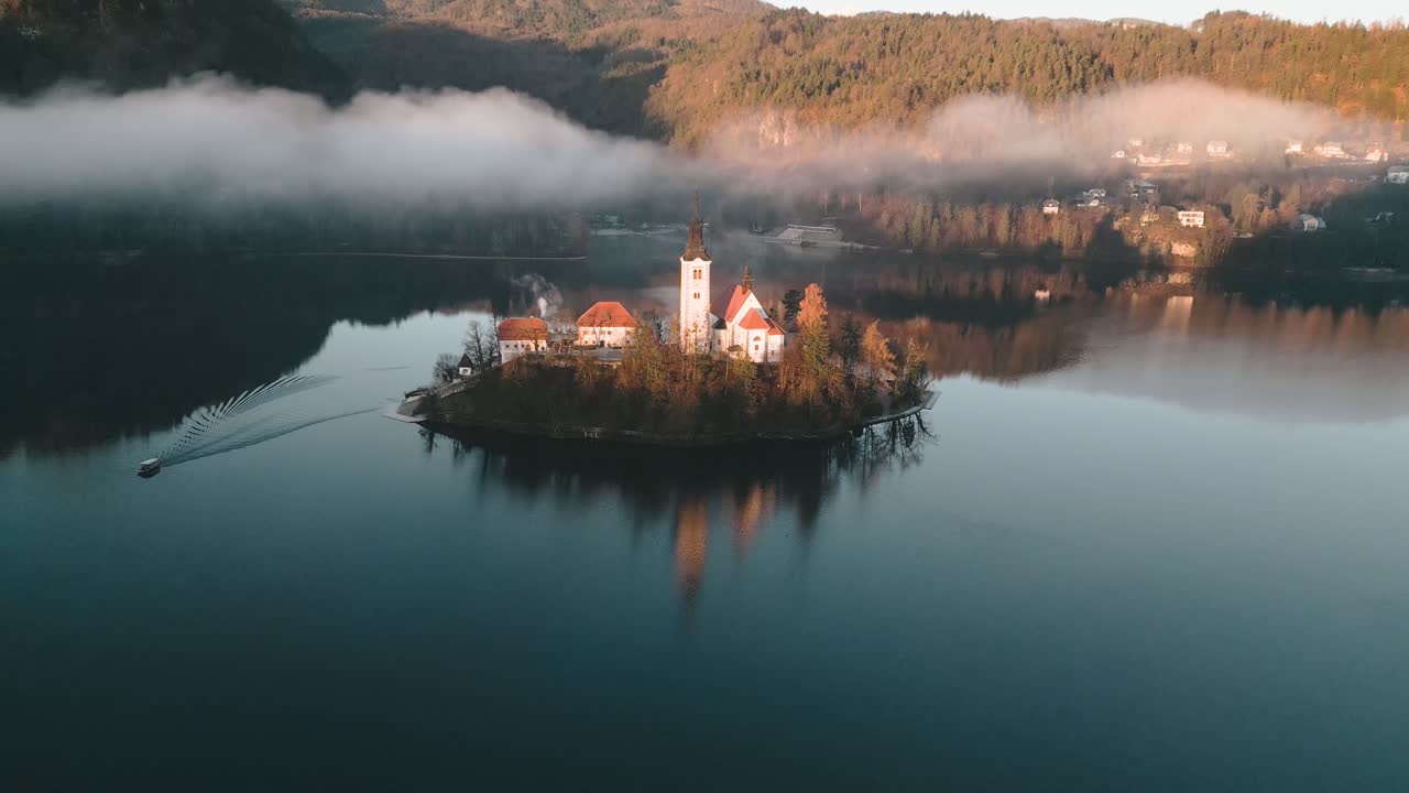 Un delicato movimento aereo si allontana e si innalza dalla tranquilla isola della chiesa che si trova al centro del magnifico lago di Bled in Slovenia, Europa Centrale.