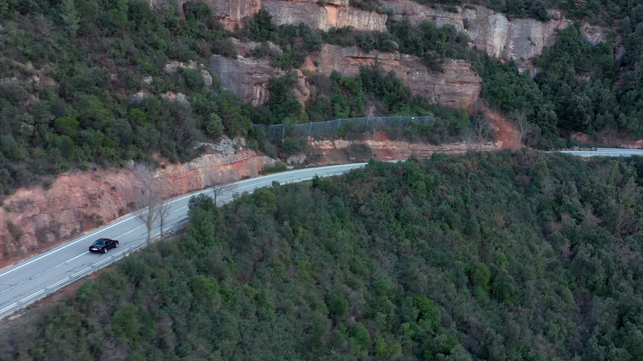 검은색 클래식 bmw e30은 바위가 많은 산악 도로를 따라 운전하며 두 명의 자전거 라이더를 건너고 있습니다.