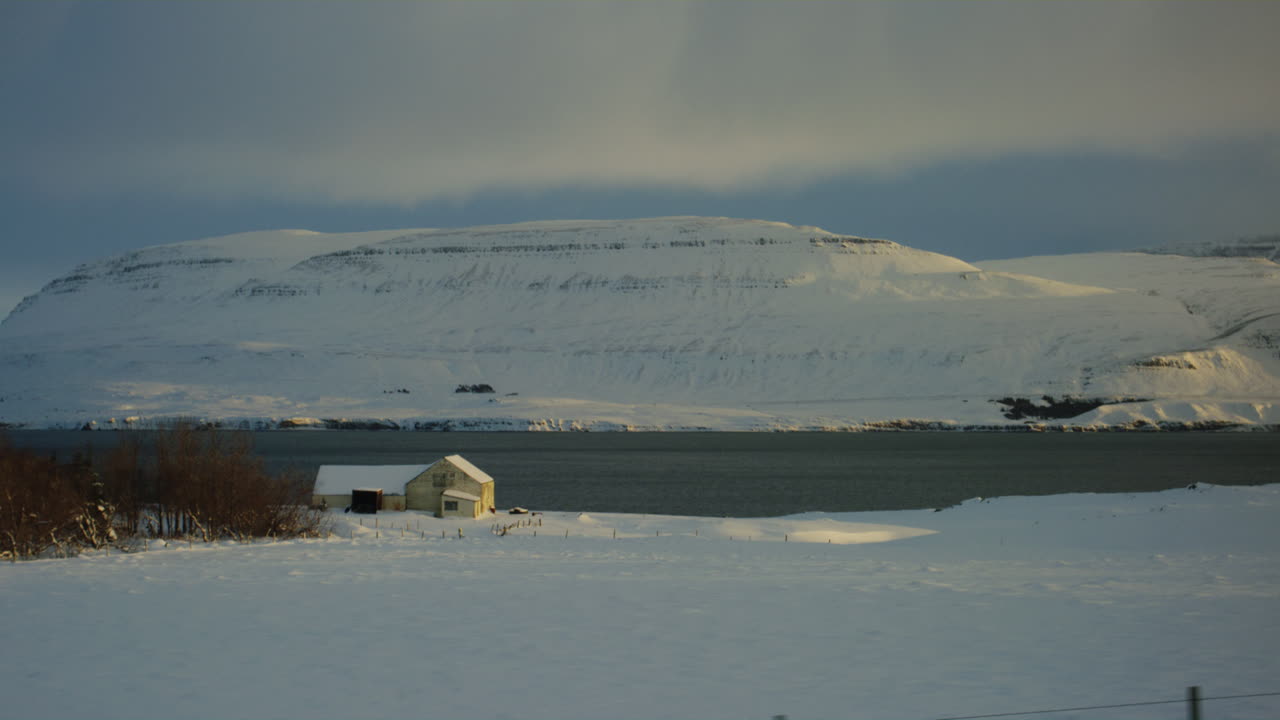 Icelandic glacier field under blue skies, icy surface contrasting against white snow as sunset sky and clouds grace mountain tops in farmlands