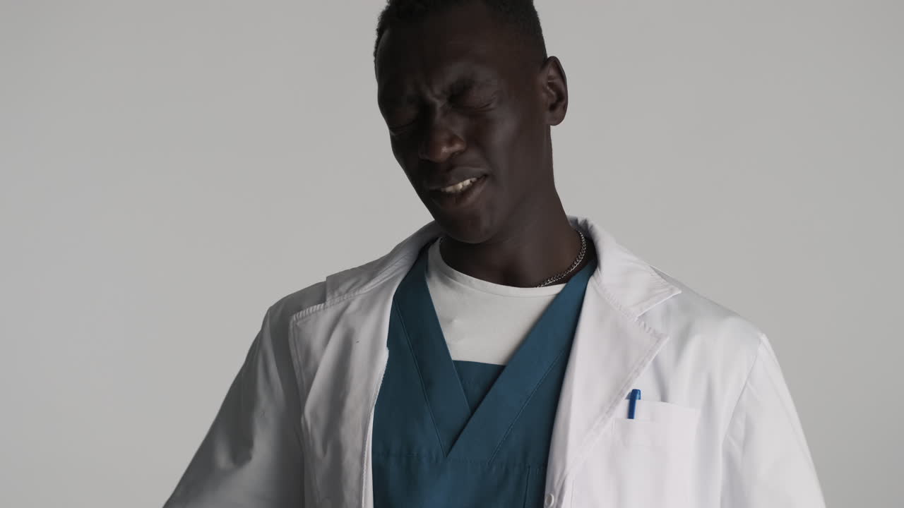 Tired African american doctor on grey background.