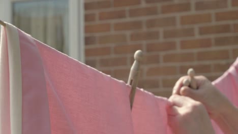 woman hanging clothes on the washing line with wooden, pegs