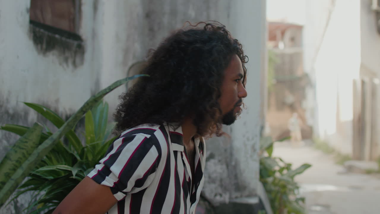 Enigmatic And cheerful black young man sits and looks around in the street of old town