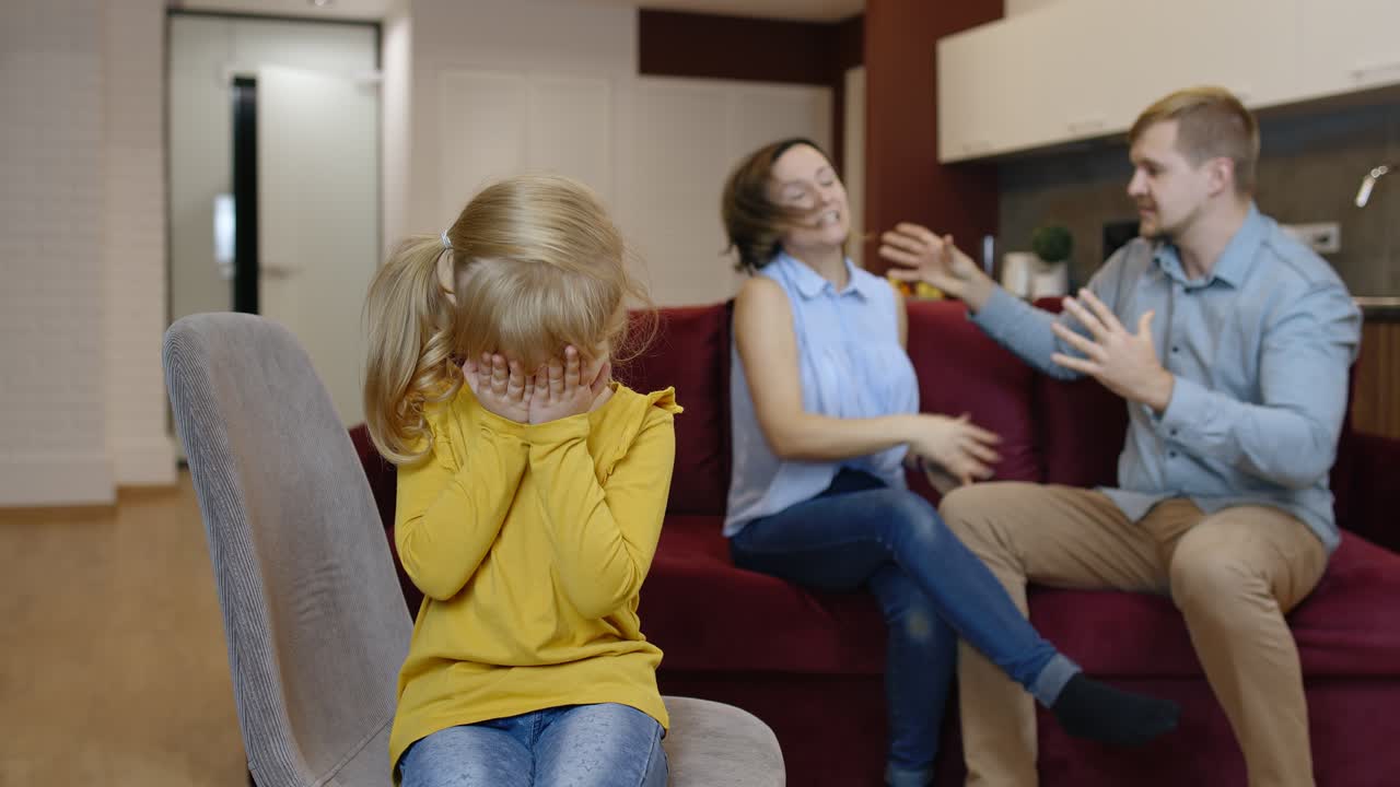 어린 소녀는 가족, 갈등, 위기에서 부모 사이의 다으로 고통 받고 울고 있습니다.