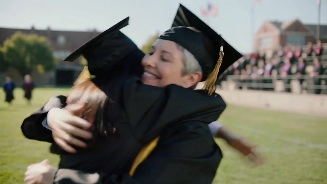 Seeing mentor, running female graduate in black gown maroon stole on campus field, embracing mentor