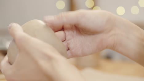 hands of unrecognizable potter smoothing surface of handmade clay vessel