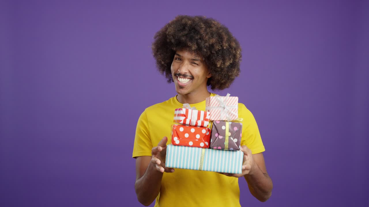 Happy Man with Afro Hair Holding a Stack of Gifts