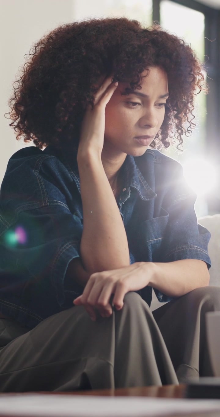Stressed Young Woman Sitting on Sofa at Home
