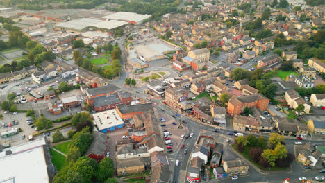 a drone records heckmondwike, uk, with industrial buildings, bustling streets, and the old town center on a summer evening