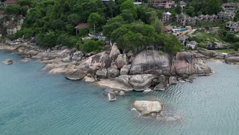 Left-to-right-pan-shot-of-a-beach-front-with-rock-and-trees-near-holiday-resort-located-Koh-Samui-Thailand