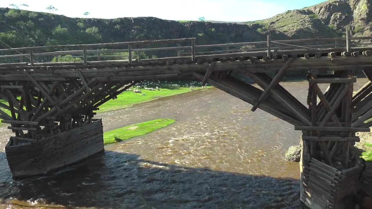 Old Wooden Bridge Over a Flowing River in a Rural Landscape