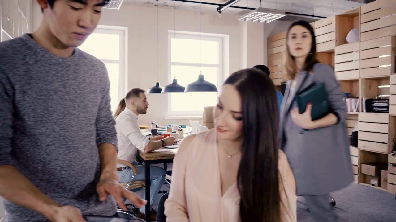 트렌디한 현대 사무실에서 카메라가 뒤로 움직입니다. 행복한 다민족 사업가들이 로프트 코워킹 4k에서 협력합니다.