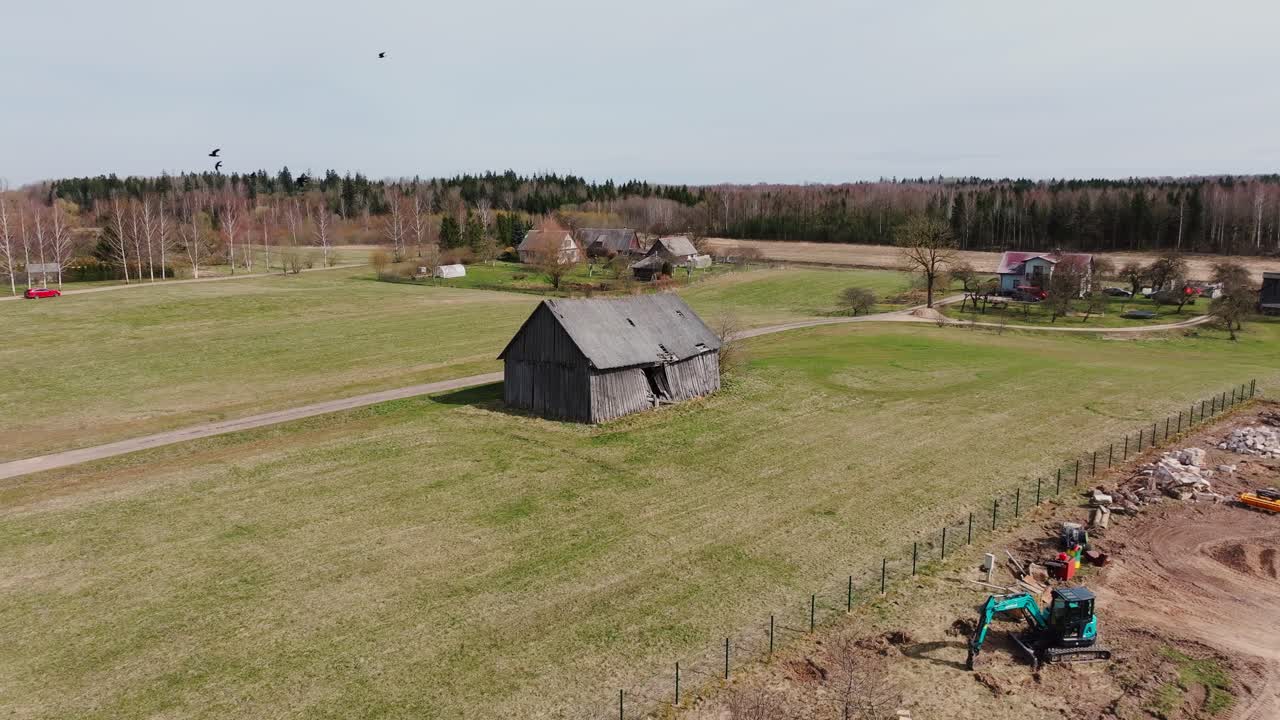 Drone glider jævnt over det landlige Letland med lade, maskiner og blødt forårslys