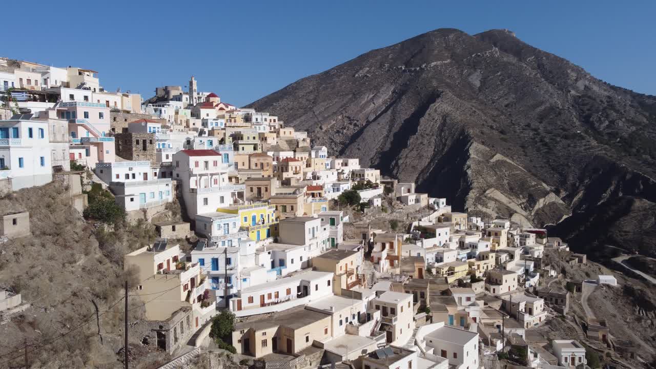 4k Cinematic Aerial Video of drone following woman to reveal Olympos Village, Karpathos: Close to Colorful Houses and Mountain