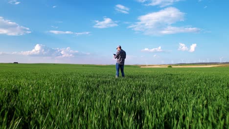 aerial zoom in view of a farmer using a digital tablet and monitoring a wheat crop on large scale vegetable farm. high quality 4k footage