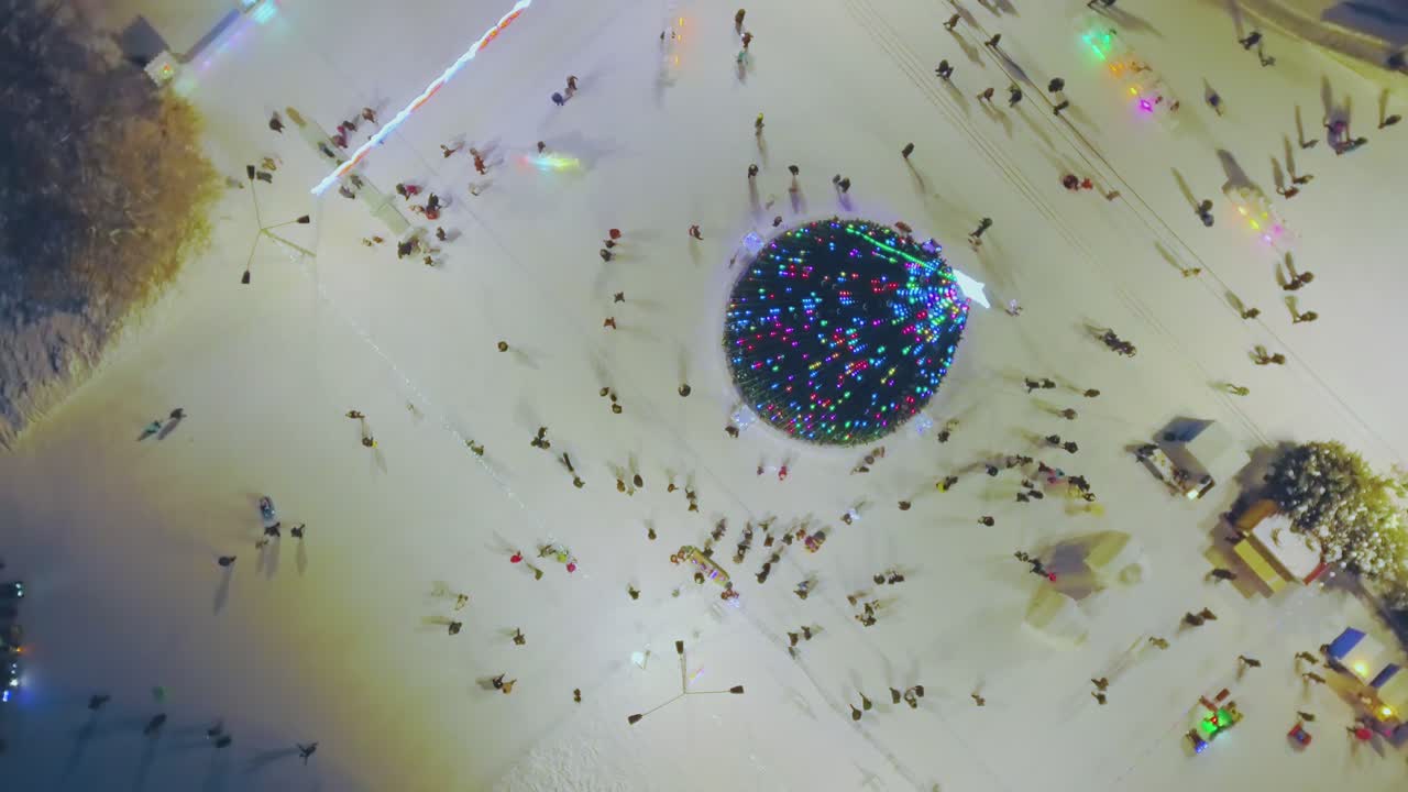 밝은 네온 불빛이 있는 크리스마스 트리와 도시 공원에 있는 사람들