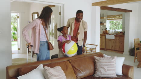 diverse family arriving at vacation home, smiling and holding beach ball