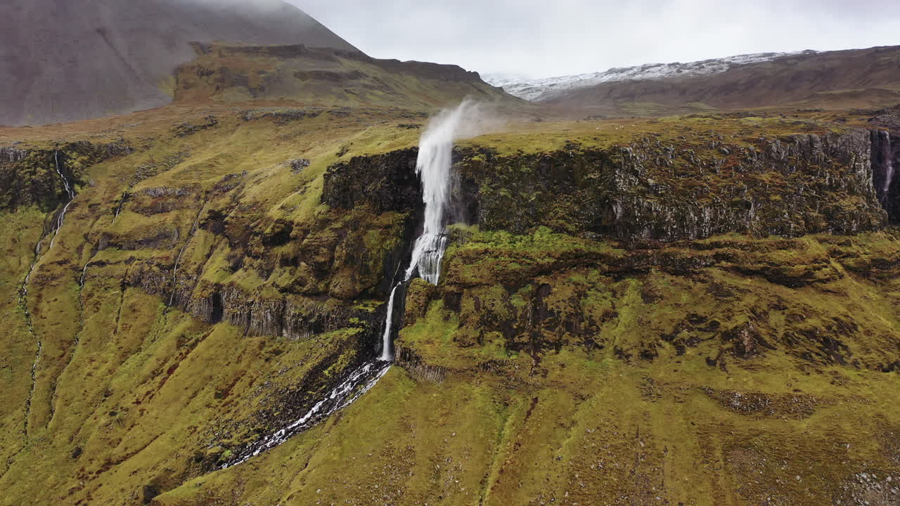 vuelo de drones hacia una cascada arrastrada por el viento en islandia