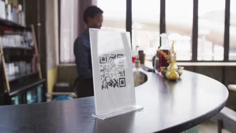 mano de un cliente usando un teléfono inteligente para leer el código qr en la barra de una cafetería