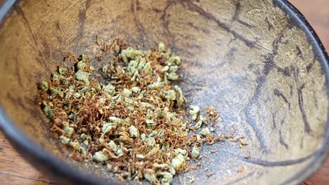 Mixed-tobacco-and-cannabis-grounds-in-a-coconut-bowl,-soft-dolly-movement