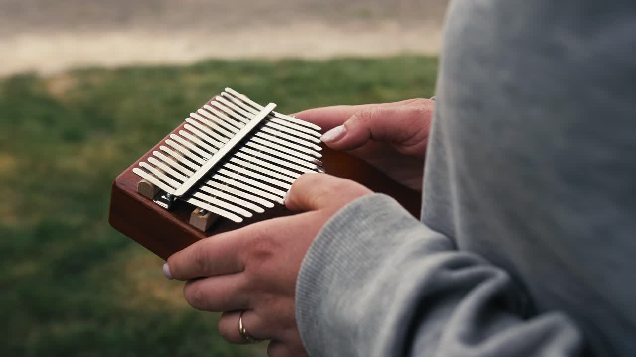 una mujer toca la kalimba al aire libre entre la vegetación