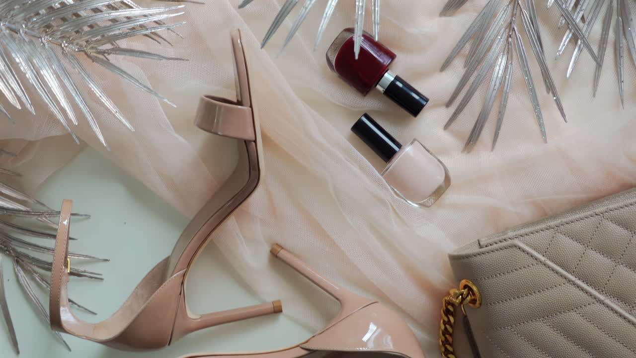 Chisinau, Moldova - June 14, 2024: Beige Yves Saint Laurent bag near a pair of strappy heels and nail polish bottles