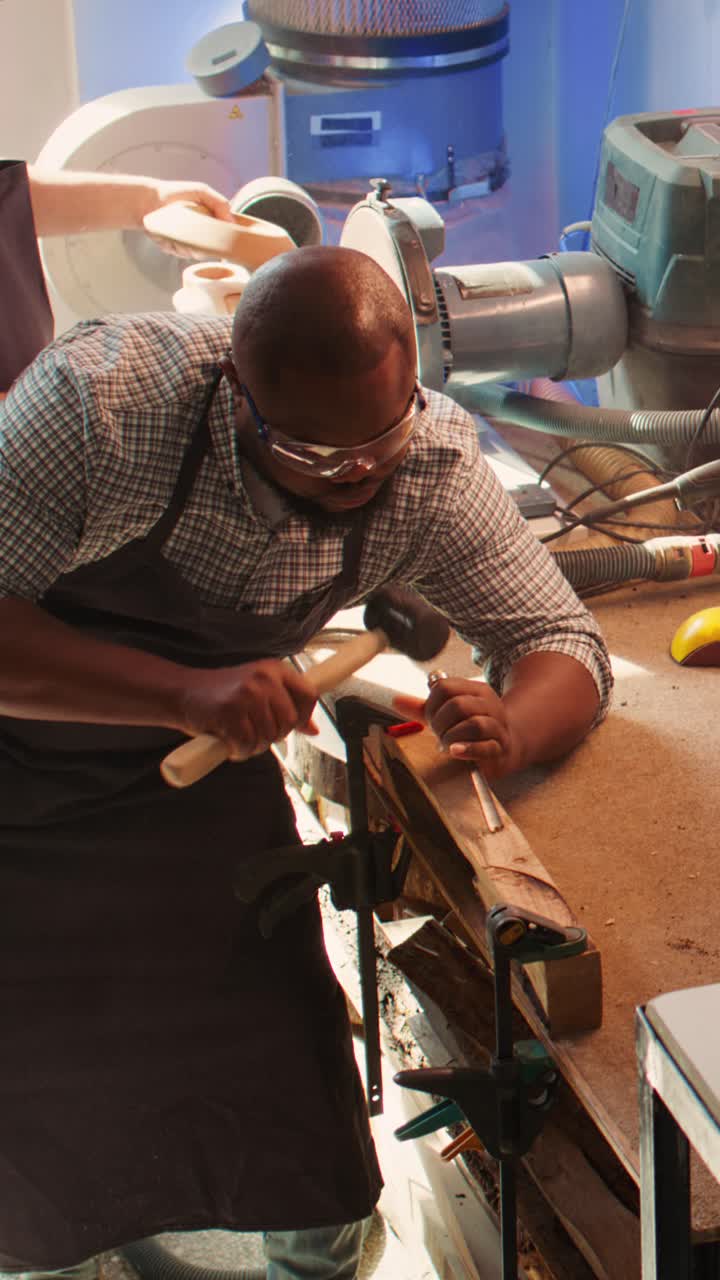 African American Man Carving Wood with Chisel and Hammer in Workshop