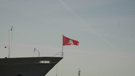 the flag of the city of hamburg waving in the wind on top of cap san diego in hamburg harbor