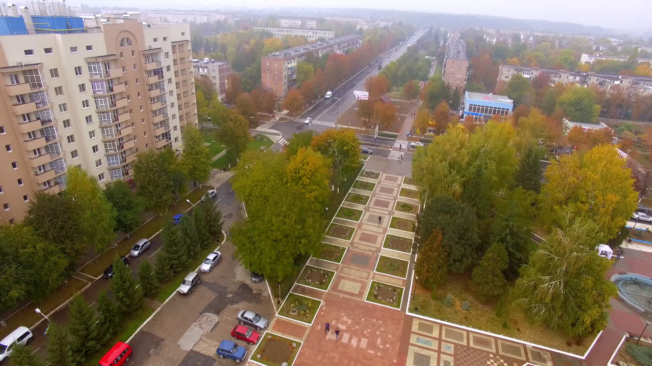Colorful park area in the downtown. Roads and buildings surrounded by trees. Autumn cloudy day background.