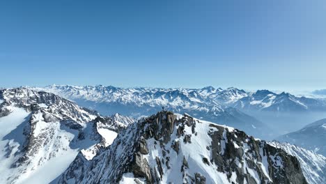 tiro de dron de un montañero de pie en un pico rocoso en los alpes