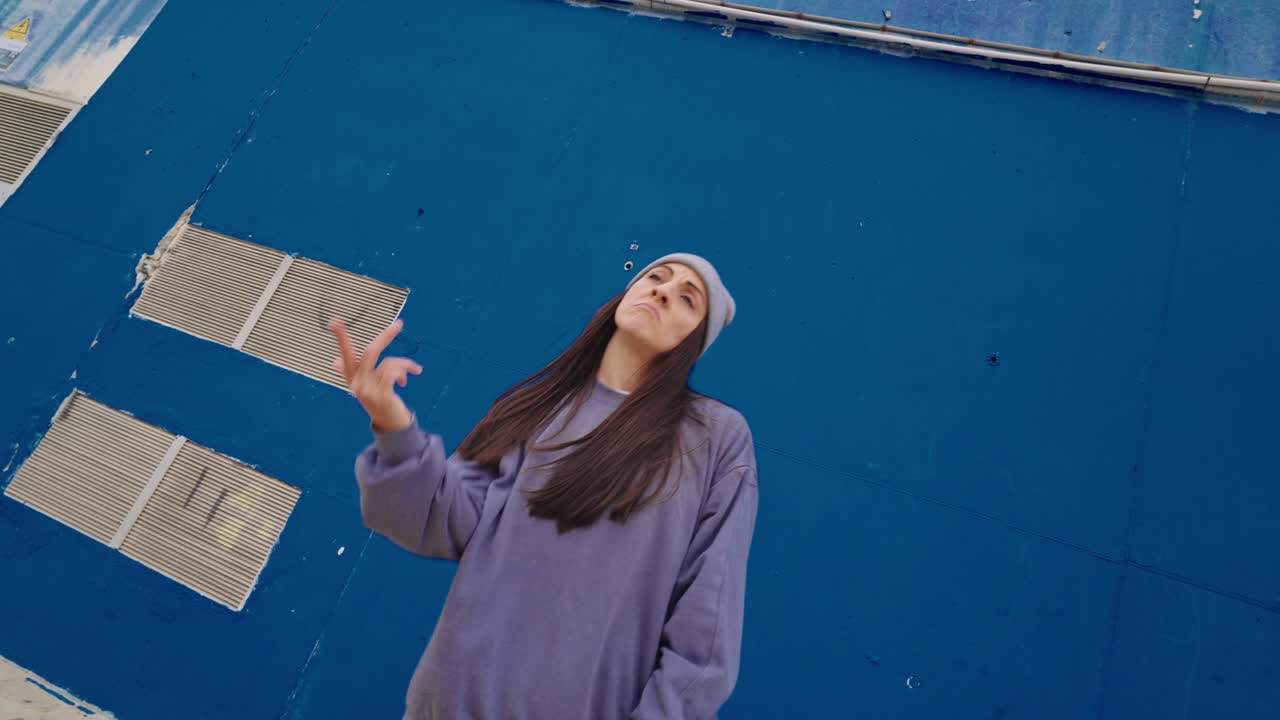 Woman dancing in front of a blue wall