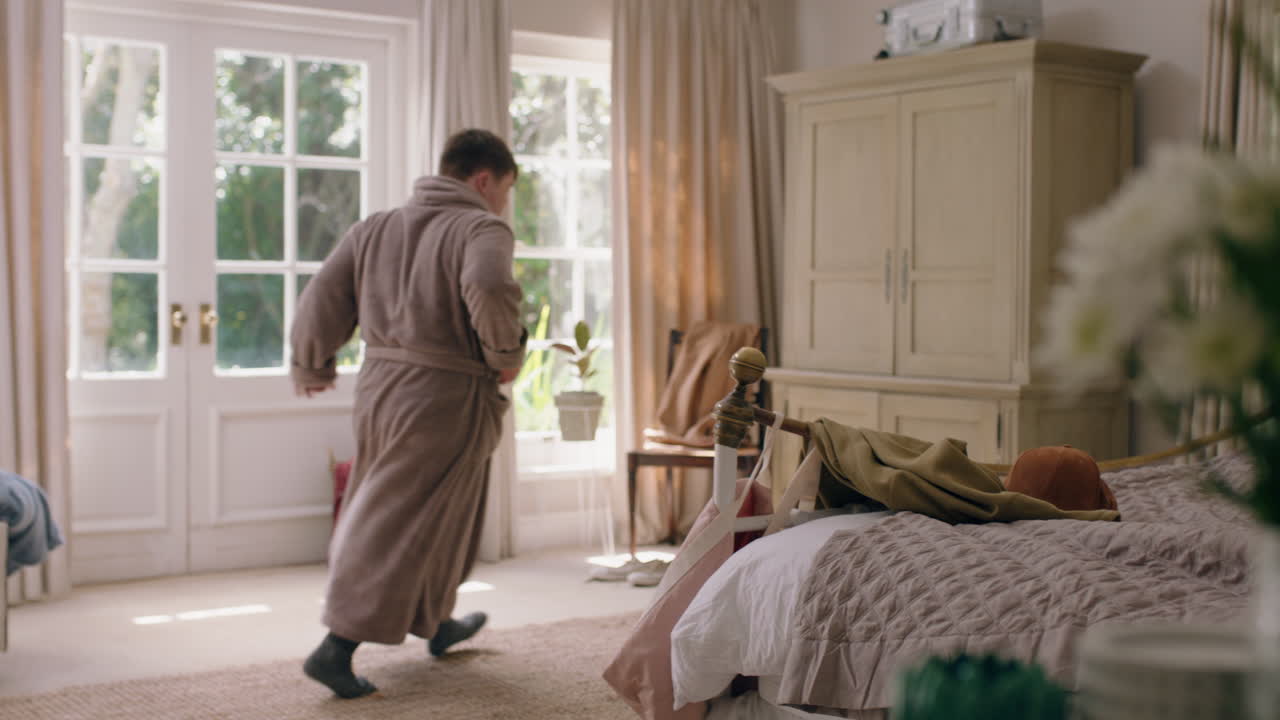 молодой подросток с синдромом дауна танцует в спальне, чувствует себя счастливым, веселится, играет, танцует, празднует дома в выходные утром