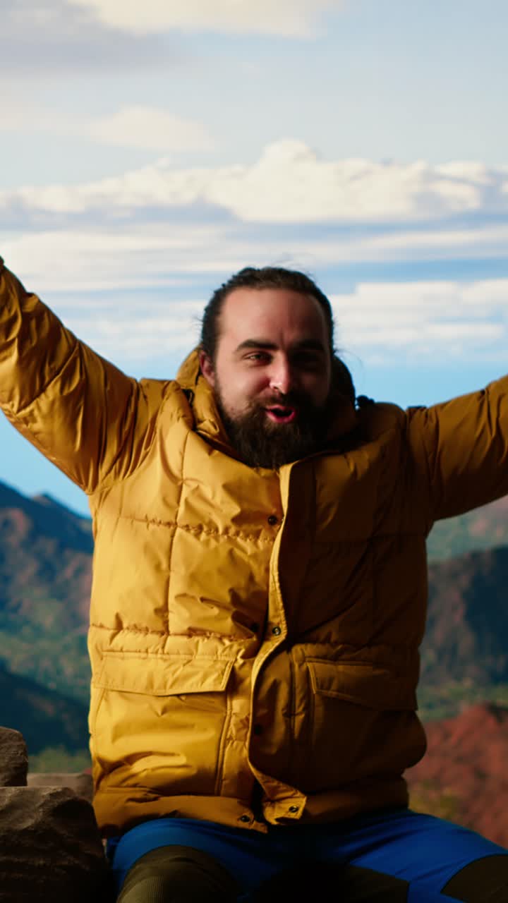 Uomo barbuto in giacca gialla che ammira la vista sulla montagna