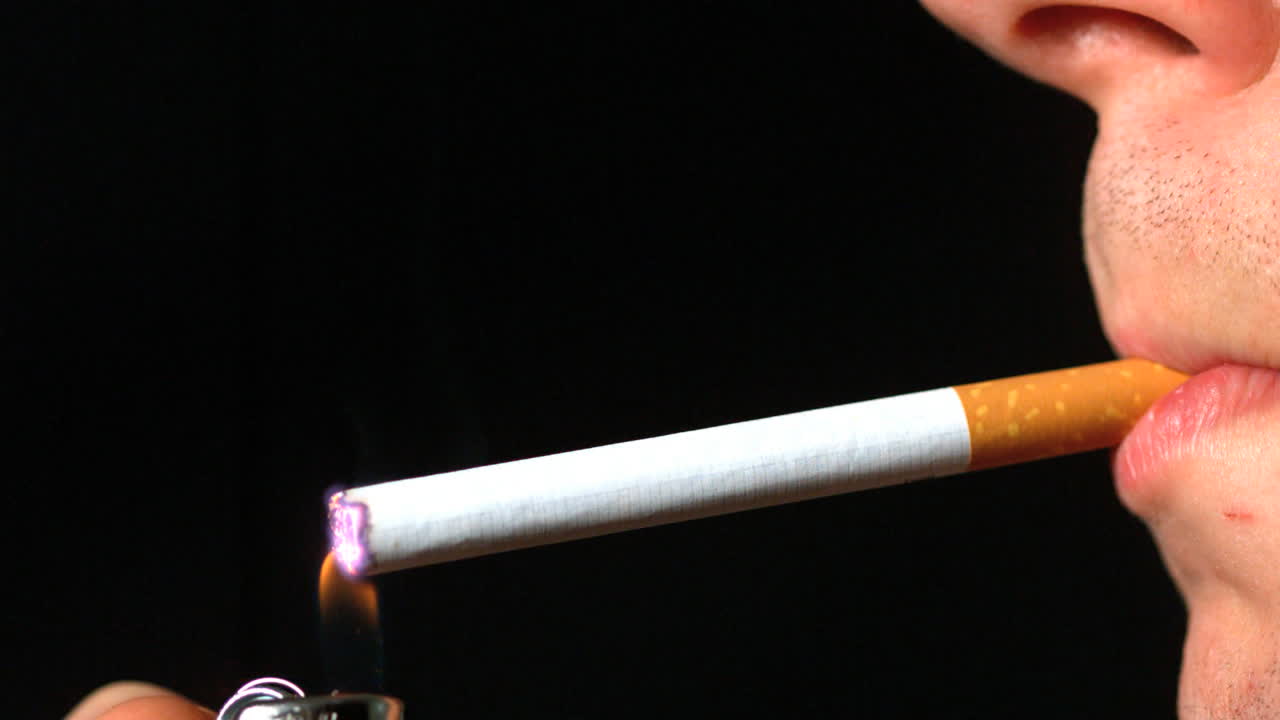 profilo lateral del hombre que enciende un cigarrillo