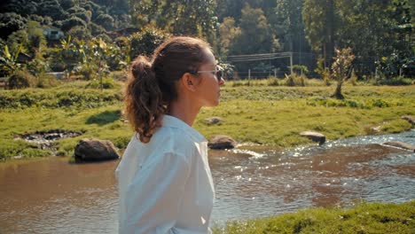woman by a river in a rural landscape