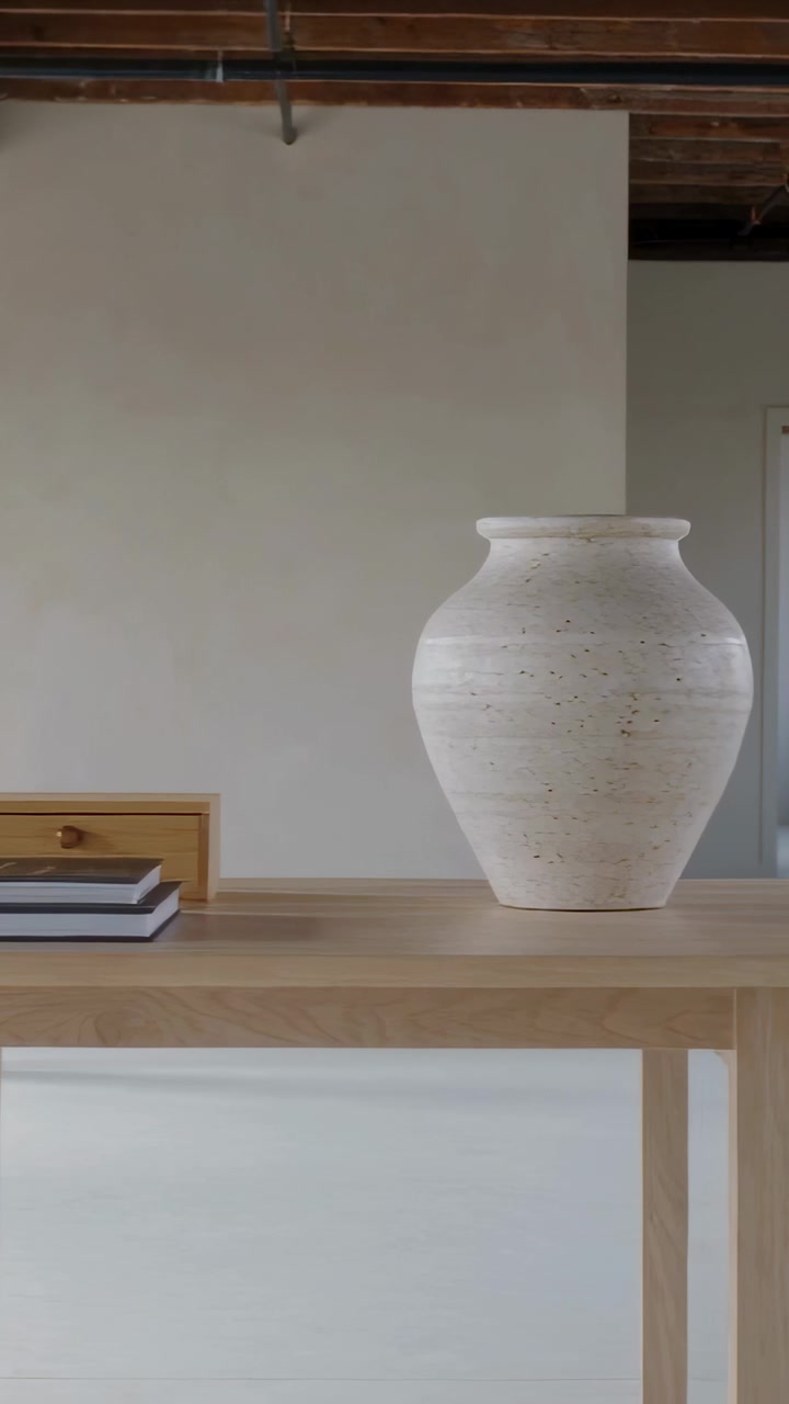 Video verticale: Telecamera che panoramica rivelando un tavolo di legno in un loft, mostrando libri, una scatola e un vaso bianco per decorazione.