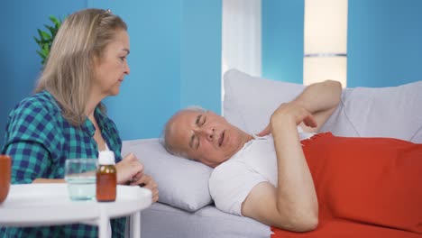 mujer dando medicina a su marido enfermo.